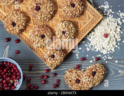Oatmeal homemade cookies with cranberry flat on wooden table with berries and oats nearby, from above overhead top view, closeup, copy space Stock Photo