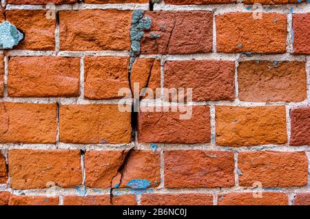 An old weathered fragment of a brick wall with cracks. Background for the designer. A large brick. Stock Photo