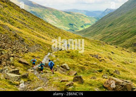 Fell runners descending Grisedale in the Eastern fells of the Lake District Stock Photo