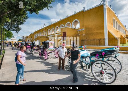 Carriages waiting for tourists at Parque Itzamna, plaza below Convento de San Antonio de Padua, monastery in Izamal, Yucatan state, Mexico Stock Photo