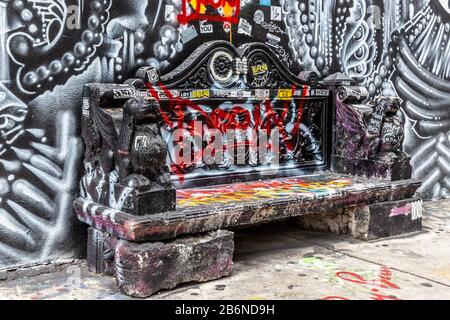 Concrete bench covered in graffities and colored spray, Wynwood neighborhood, Miami, Florida, USA. Stock Photo