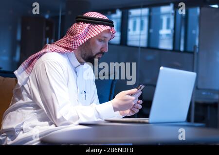 A Middle Eastern businessman typing on the phone in his office. Businessman Arabic using mobile phone for connection to communication.Business Technol Stock Photo