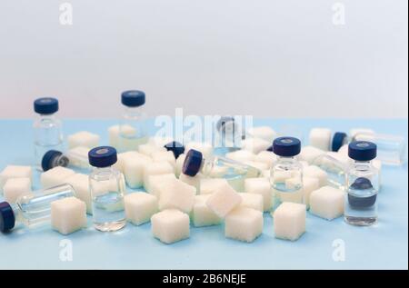 Sugar addiction, insulin resistance, unhealthy diet, sugar cubes and bottles of insulin on blue background, diabetes protection medical concept Stock Photo