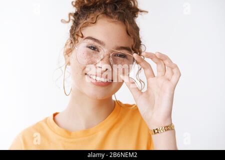 Close-up attractive happy redhead girl freckles messy hairbun touching glasses smiling white teeth pick new eyewear optician store, standing joyful Stock Photo