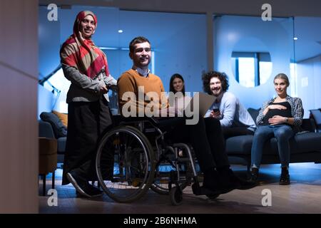 Handicapped young man with colleagues working in office. He is smiling and passionate about the workflow. Performing in co-working space. Office peopl Stock Photo