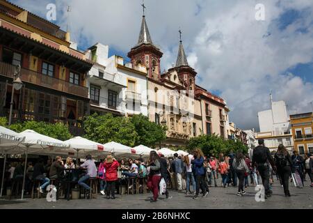 Crowded bar terraces in front of Nuestra Señora de la Paz Hospital in Salvador Square, Seville, Spain Stock Photo
