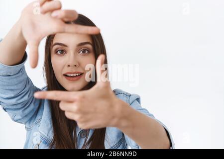 Amused, inspired fascinated young creative female searching perfect angle, making hand frames, looking through to find right perspective, smiling Stock Photo