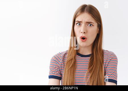 Close-up shocked and freak-out, concerned young serious-looking woman stare skeptical and confused, say what, open mouth gasping alarmed, frowning Stock Photo