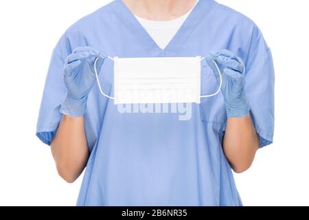 Unrecognizable surgeon in scrubs and surgical gloves holding face mask and standing against white background, protection concept Stock Photo