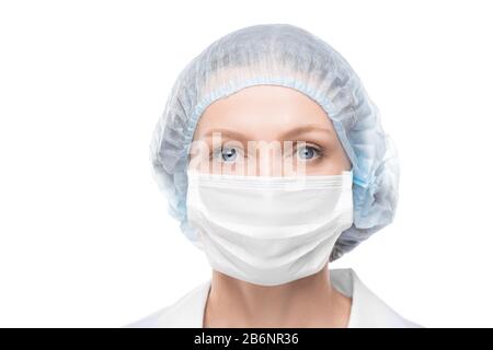 Portrait of lady doctor with blue eyes wearing face mask and surgical cap against white background Stock Photo
