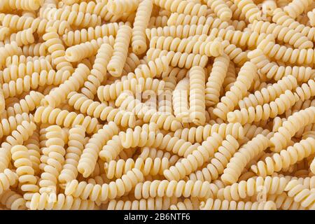 Uncooked fusilli corti bucati pasta background Stock Photo