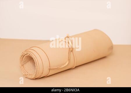 A roll of vegetable tanned raw leather on rolled up on white background Stock Photo