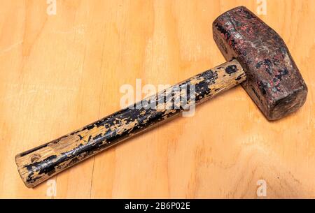 A heavily used and weathered mallet hammer on a stained wood background Stock Photo