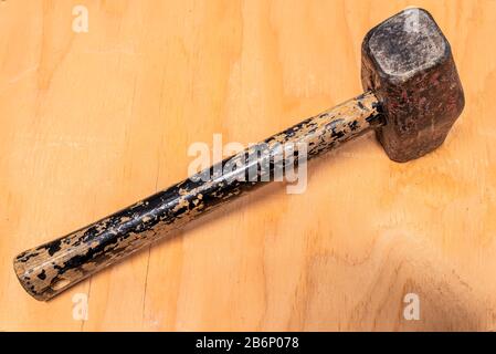 A heavily used and weathered mallet hammer on a stained wood background Stock Photo