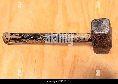 A heavily used and weathered mallet hammer on a stained wood background Stock Photo