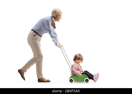 Mother pushing her little toddler daughter in a wooden toy cart isolated on white background Stock Photo