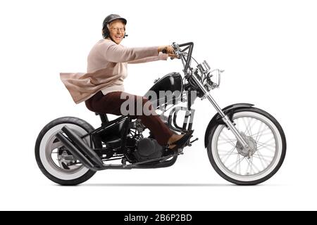 Senior woman riding a custom chopper motorbike and smiling at camera isolated on white background Stock Photo