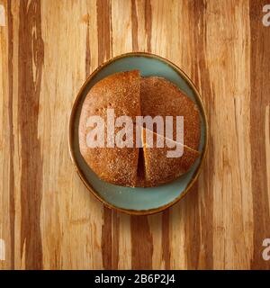 flatlay traditional dark bread loaf on a plate with slices, on a wooden table and copy space for text Stock Photo