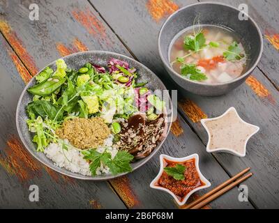 Organic asian healthy food. Buddha bowl with salmon fish soup, salad, rice with pesto, spinach leaves, green beans, beef with teriyaki sauce. Close up Stock Photo