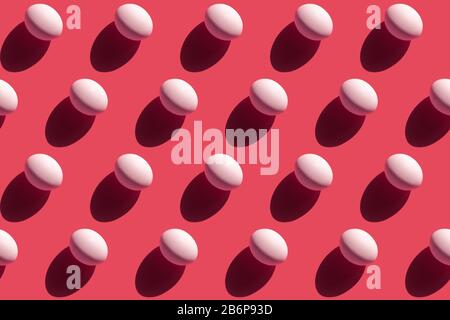 Repeating white eggs with a hard shadow on a pink background, easter background in pop art style Stock Photo