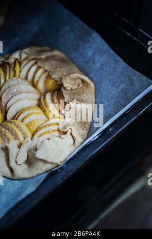 Raw apple galette - pie on white baking parchment. Copy space, flat lay. Stock Photo