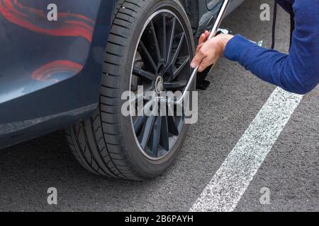 Close up mans hands changing a wheel using screwdriver. Replacing winter and summer tires. Seasonal tire replacement concept. Service process. Prague Stock Photo