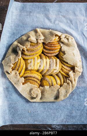 Raw apple galette - pie on white baking parchment. Copy space, flat lay. Stock Photo