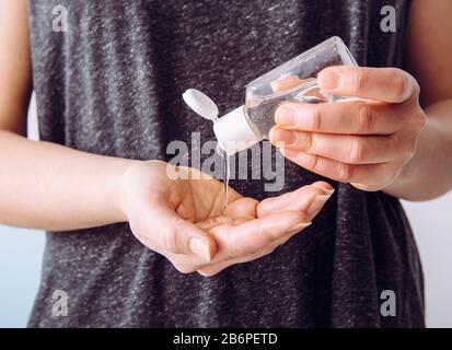 Close up view of woman person using small portable antibacterial hand sanitizer on hands. Stock Photo