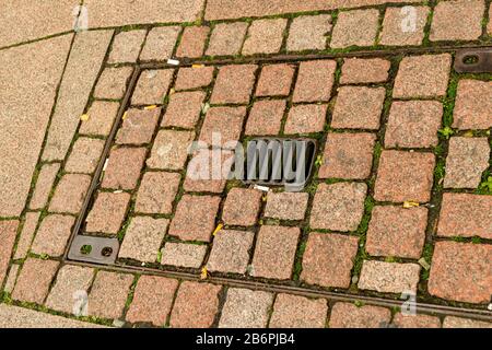 Manhole cover walled in cobblestones on the street Stock Photo