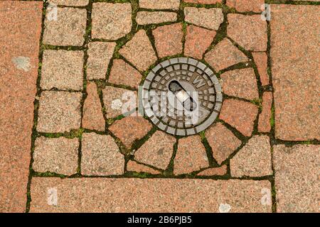 Manhole cover walled in cobblestones on the street Stock Photo