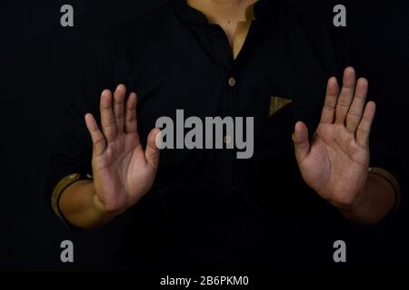 Asian man muslim takbir and solat take his hands up. Islamic praying concept on black background. Selective focus on arms and finger Stock Photo