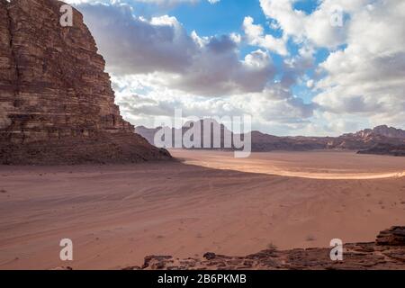 Kingdom of Jordan, Wadi Rum desert, sunny winter day scenery landscape with white puffy clouds and warm colors. Lovely travel photography. Beautiful desert could be explored on safari. Miniature car Stock Photo