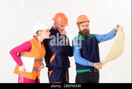 Team of builder, engineer, architect work on project. Men and woman in helmets, architects on thoughtful faces looks at drawing, plan, blueprint, project, white background. Engineering concept. Stock Photo