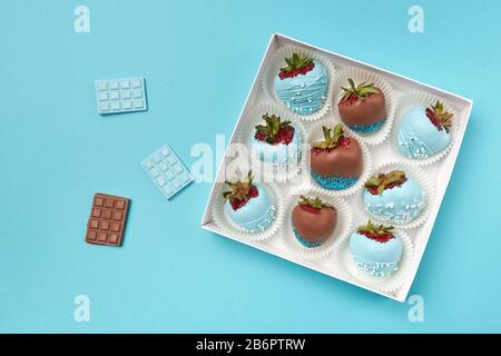 Tasty dessert in the form of ripe strawberries in chocolate on a turquoise background. Stock Photo