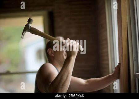 Male builder hammering a nail with a hammer. Stock Photo