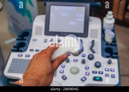 Doctor's hand holding ultrasound probe of ultrasound scanner for medical diagnostics. Stock Photo