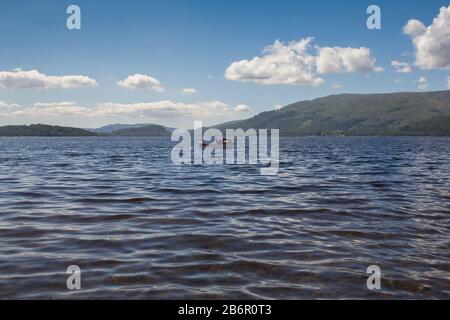 A two men out fishing in a boat on Loch Lomond in the Scottish Highlands on a summers day Stock Photo