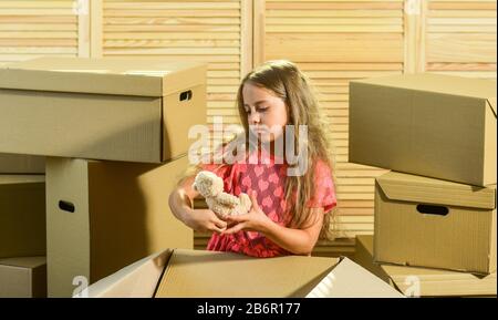 Packaging things. Stressful situation. Divorce and separation. Family problem. Prepare for moving. Moving out. Moving routine. Only true friend. Girl child play with toy near boxes. Move out concept. Stock Photo