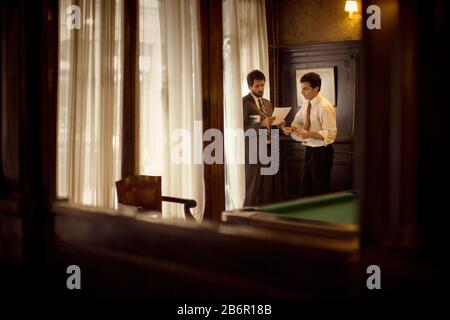 View of two businessmen through mirror discussing work. Stock Photo