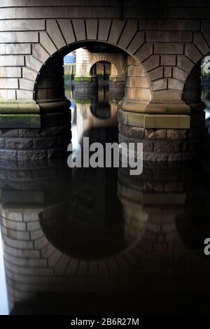 The archways bellow a bridge on the river Clyde in Glasgow on a siummer morning in Scotland Stock Photo