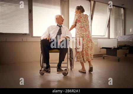 View of a man on wheelchair talking to an elderly woman. Stock Photo