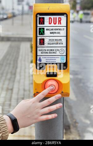Istanbul, Turkey - February 11, 2020: A female hand presses a button at a pedestrian crossing, after which you need to wait for the permission signal Stock Photo