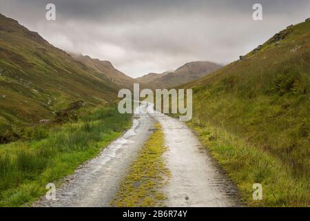 Dirt road through the Trossachs mountain range in Scotland on a windy cold and very wet Autumn day Stock Photo