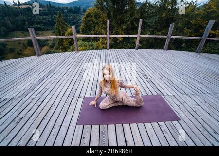 A woman practices yoga at the morning in a terrace on a fresh air. Stock Photo