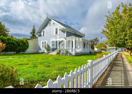 A Victorian cottage with a white picket fence and covered front porch and deck in the Spokane, Washington area of the Inland Northwest, USA. Stock Photo