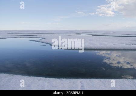 Broken pans of sea ice on ocean coast with blue sky and clouds along the Northwest Passage in June, Cambridge Bay, Nunavut Stock Photo