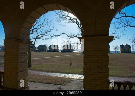 Silhouettes of officer's row homes lining the shore at Sandy Hook Bay are viewed from the portico of an unoccupied building behind them Stock Photo