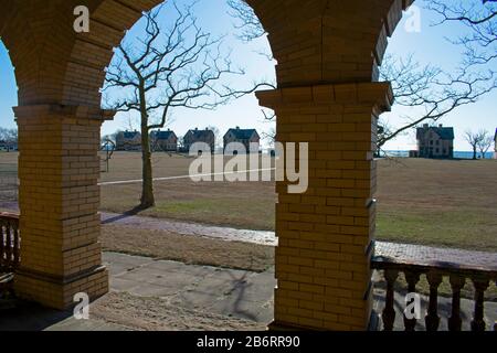 Silhouettes of officer's row homes lining the shore at Sandy Hook Bay are viewed from the portico of an unoccupied building behind them Stock Photo