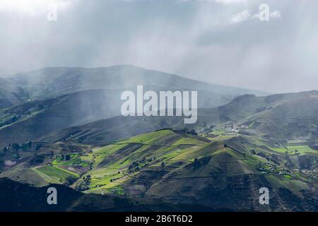 Dramatic landscape of the Andes mountains with green agriculture fields and rainfall near Quito, Ecuador. Stock Photo