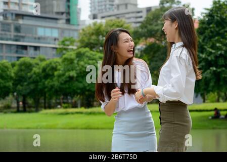 Two happy young beautiful Asian teenage girls having fun together at the park Stock Photo